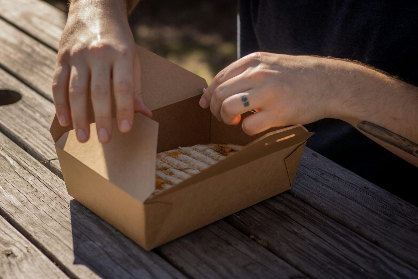 Close-up of hands applying stretch wrap on a cardboard box on a wooden pallet