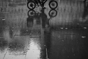 Réflexion d'un cycliste sur chaussée mouillée, illustrant comment LL Transport gère les charges lourdes même en période humid