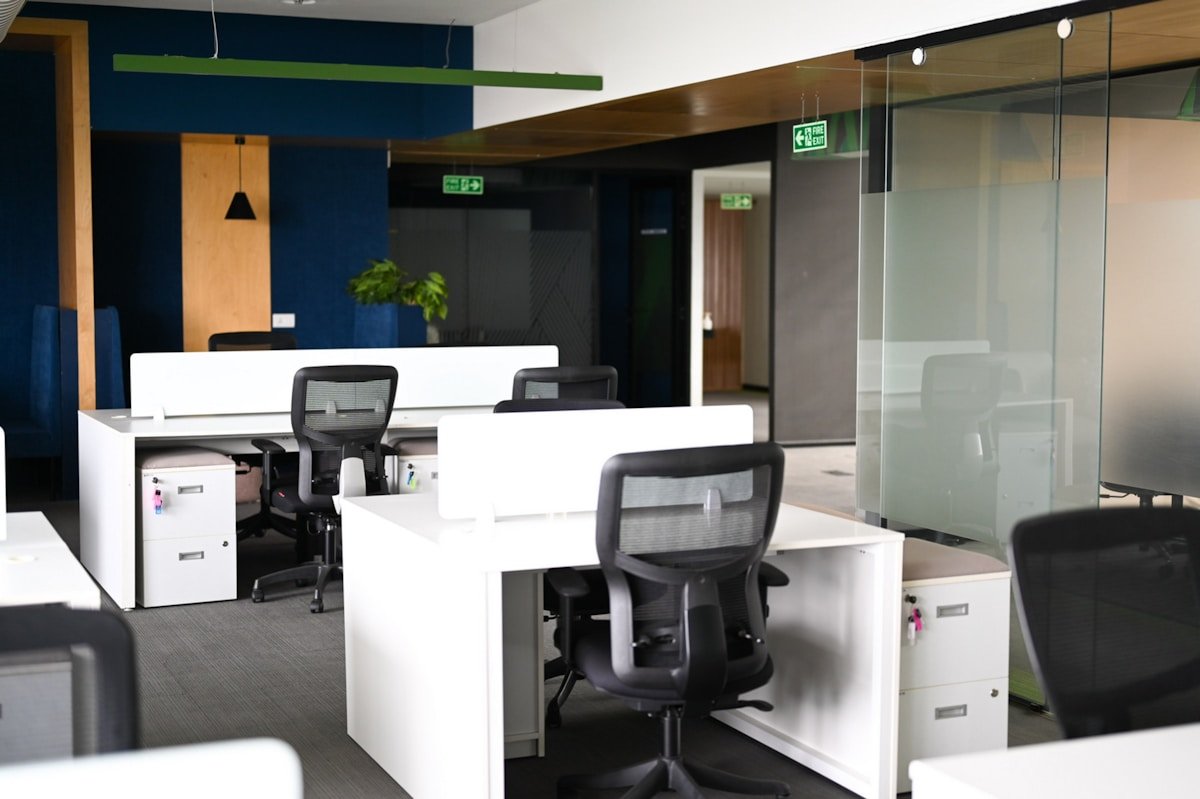 Bureau moderne avec des bureaux blancs et des chaises noires.