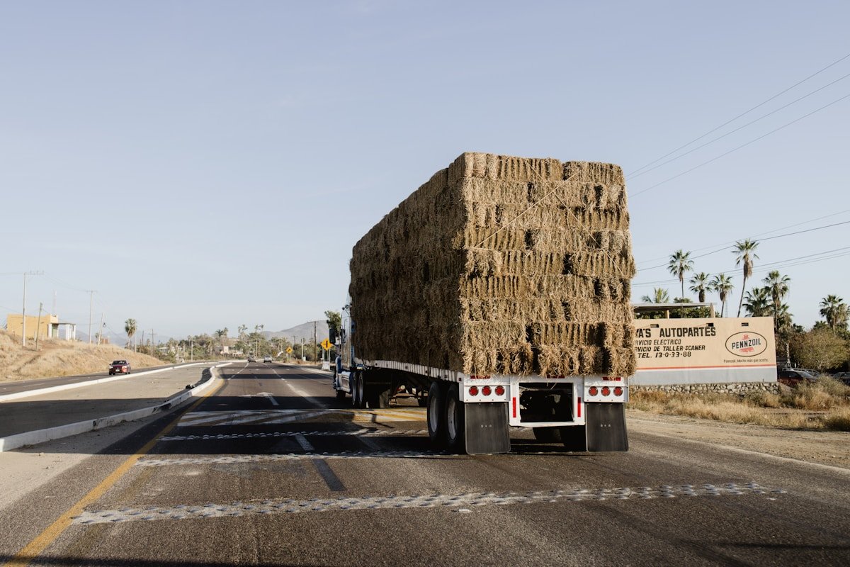 Camion transportant un chargement volumineux de bottes de foin sur l'autoroute.
