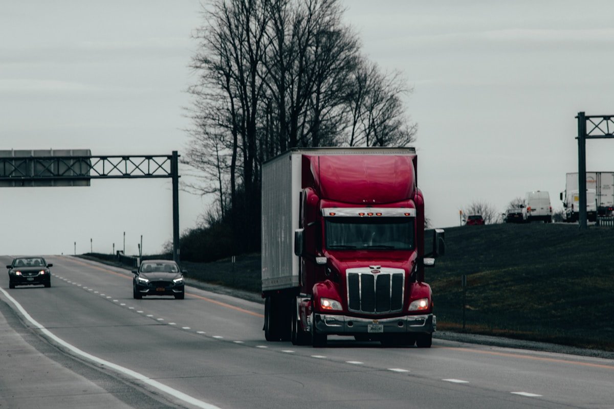 Camion rouge sur l'autoroute avec des voitures en arrière-plan.