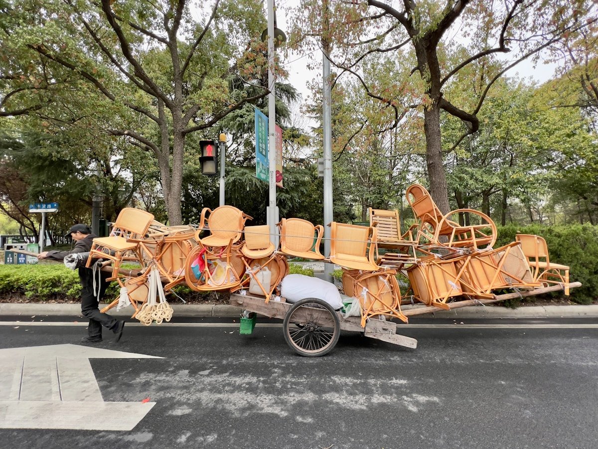 Chariot rempli de chaises en osier dans un parc boisé.