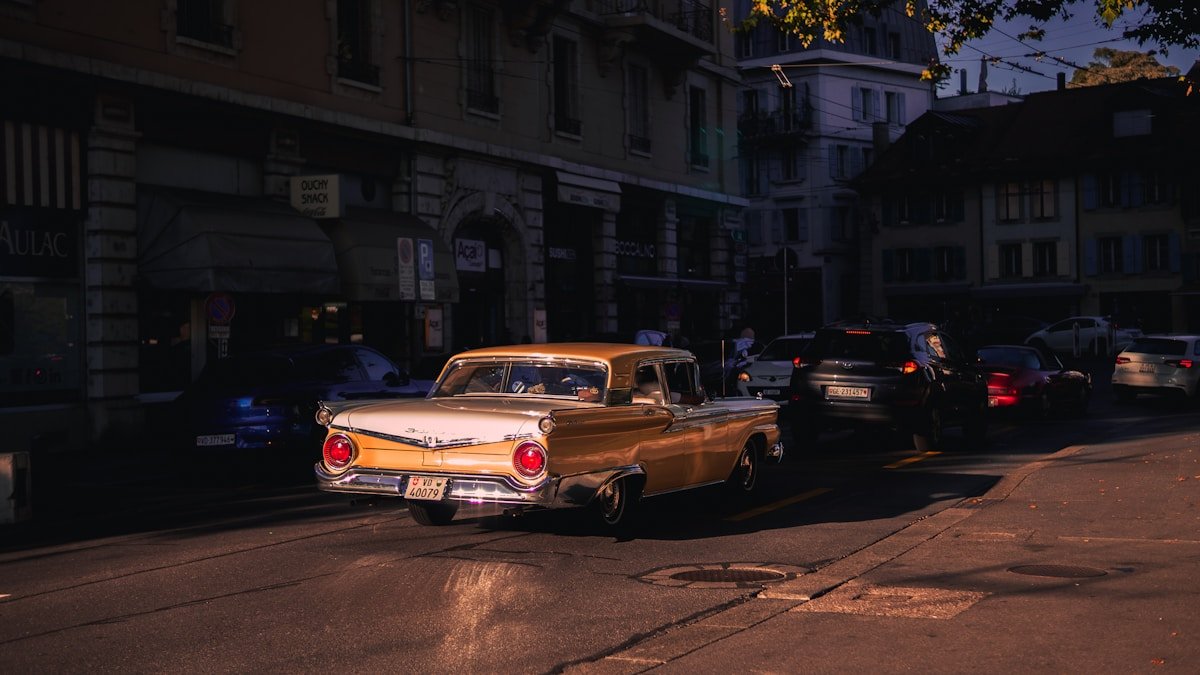 Voiture vintage dorée garée dans une rue sombre et animée.