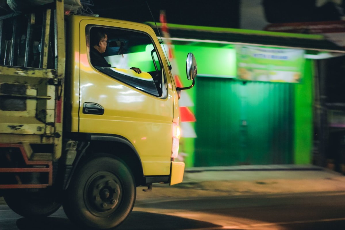 Camion de livraison jaune en mouvement dans un environnement sombre.