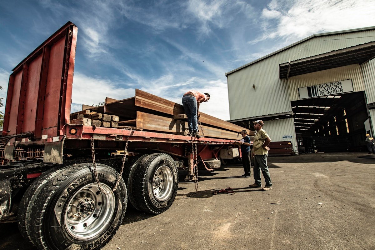 Trois hommes debout à côté d'une remorque de véhicule rouge.
