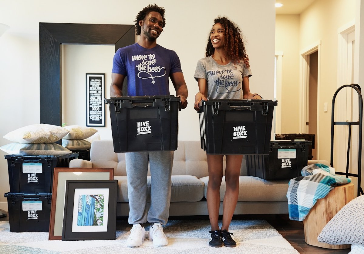 Couple souriant portant des t-shirts avec un message écologique, entouré de boîtes de rangement.