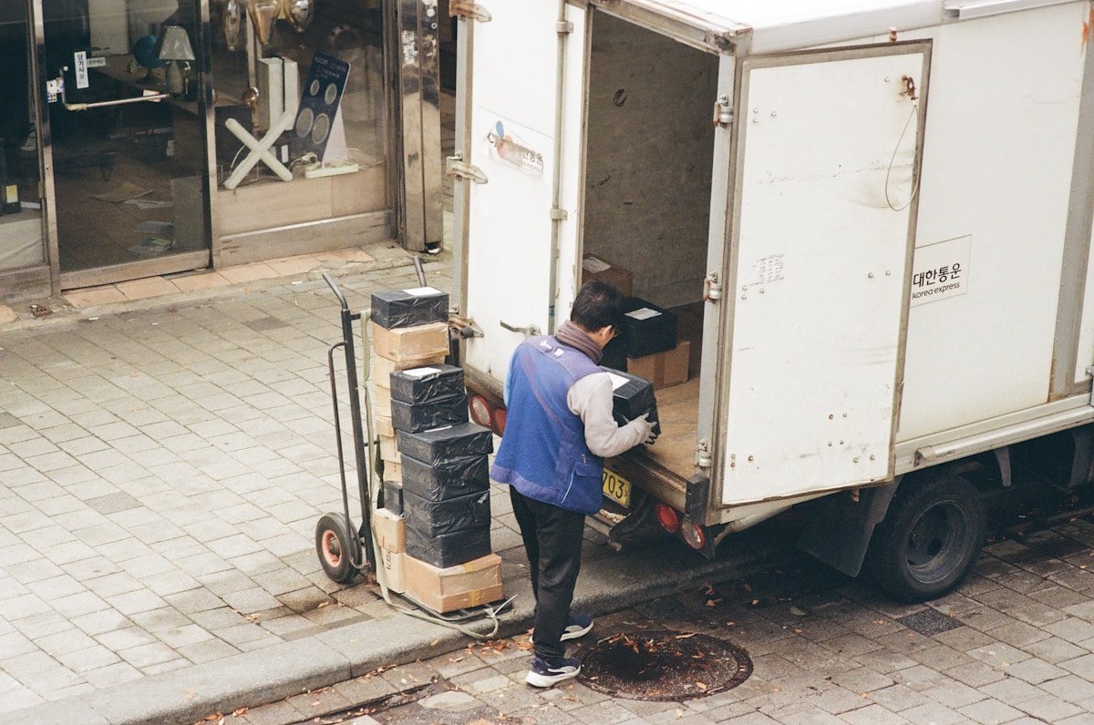 Un livreur charge des boîtes dans un camion de livraison.