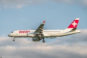 "Avion de ligne volant dans un ciel nuageux, pour trouver un transporteur aérien fiable en Suisse."