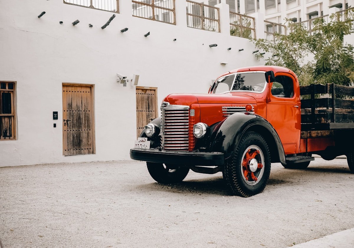 Camion vintage rouge garé dans une cour.