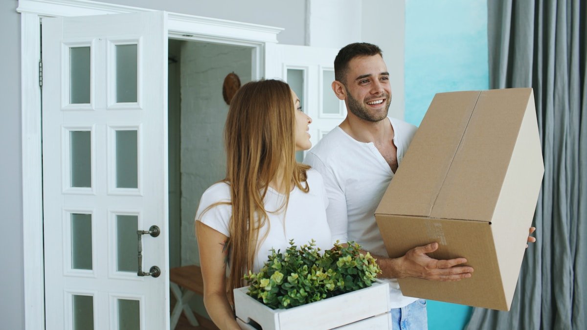 Couple heureux déménageant dans un nouvel appartement avec des boîtes.