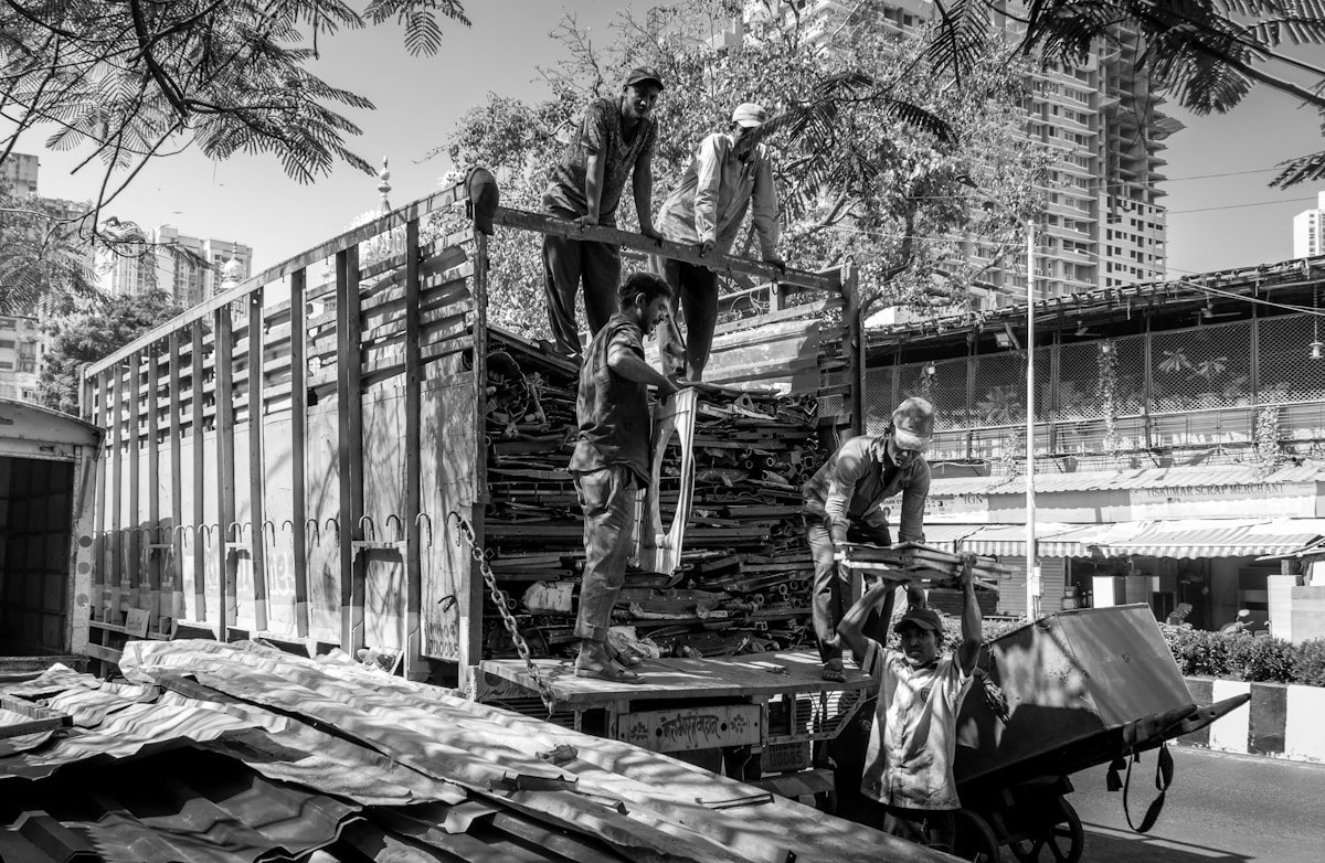 Travailleurs déchargeant du bois dans un environnement urbain.