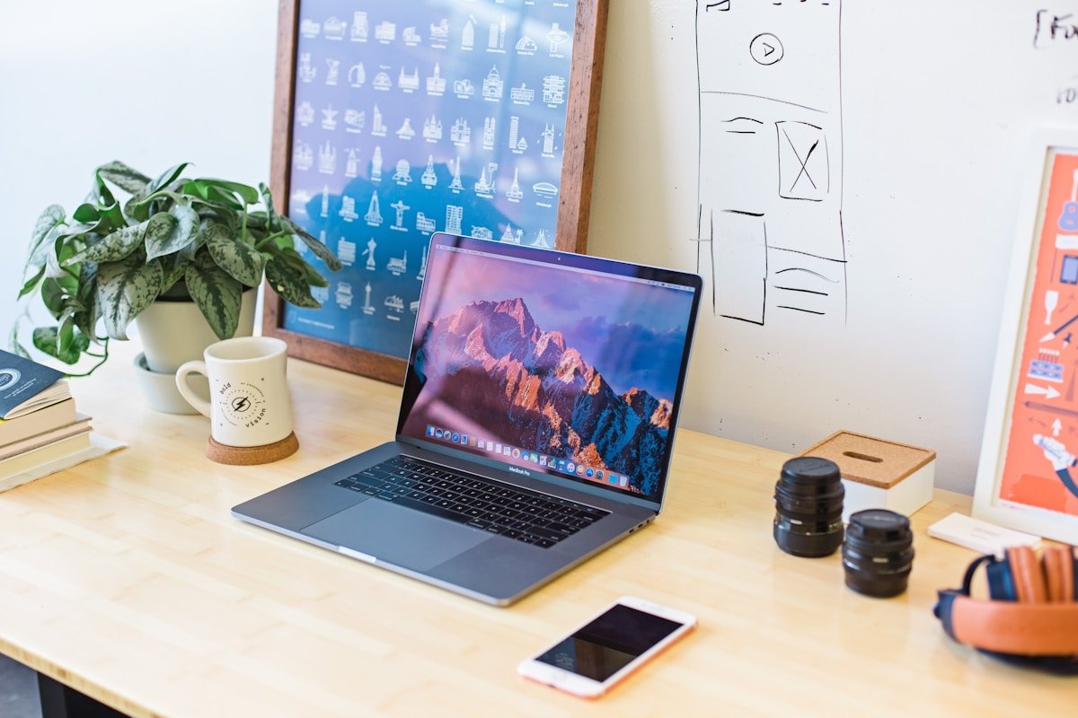Bureau de travail avec ordinateur portable, plante, tasse et accessoires.