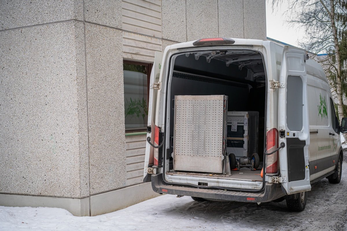 Fourgon de service avec équipement de travail garé devant un bâtiment.