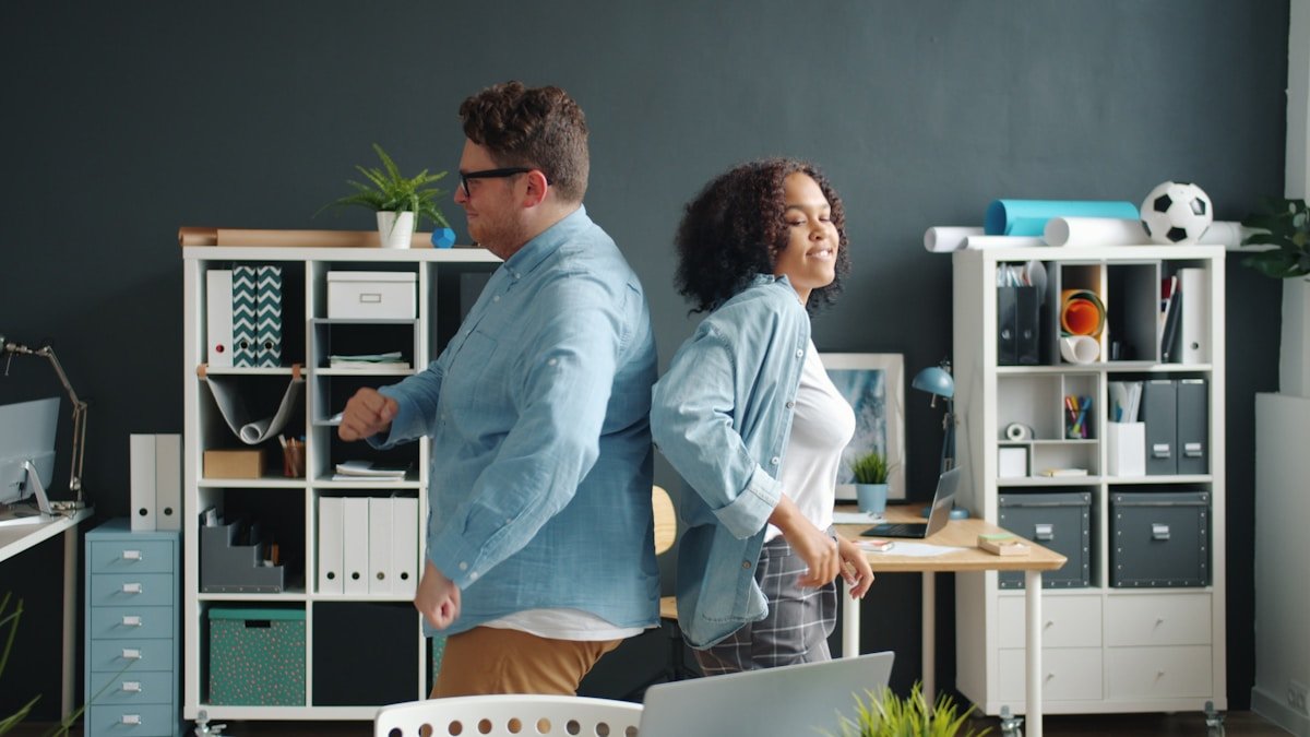 Deux personnes dans un bureau moderne, souriant et se tenant la main.