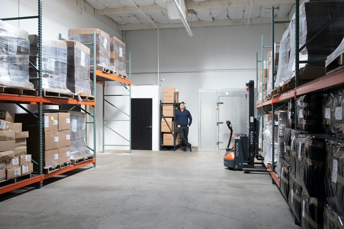 Entrepôt industriel avec étagères, chariot élévateur et employé.
