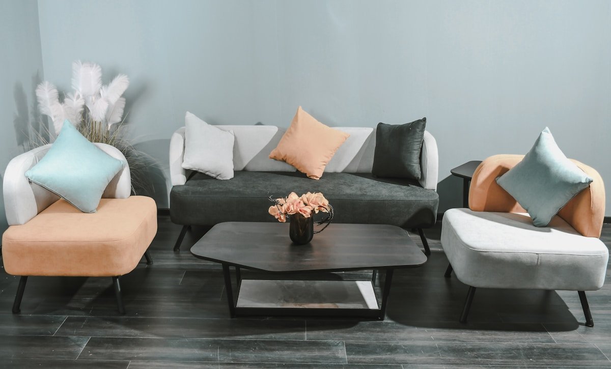 Salon moderne avec canapé gris, fauteuils colorés et table basse.