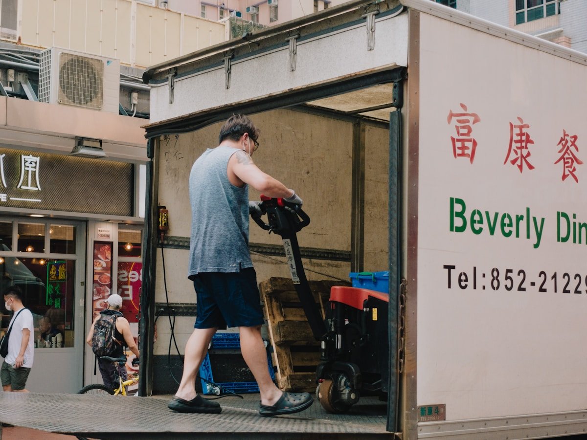 Homme chargeant un camion de livraison devant un restaurant chinois.