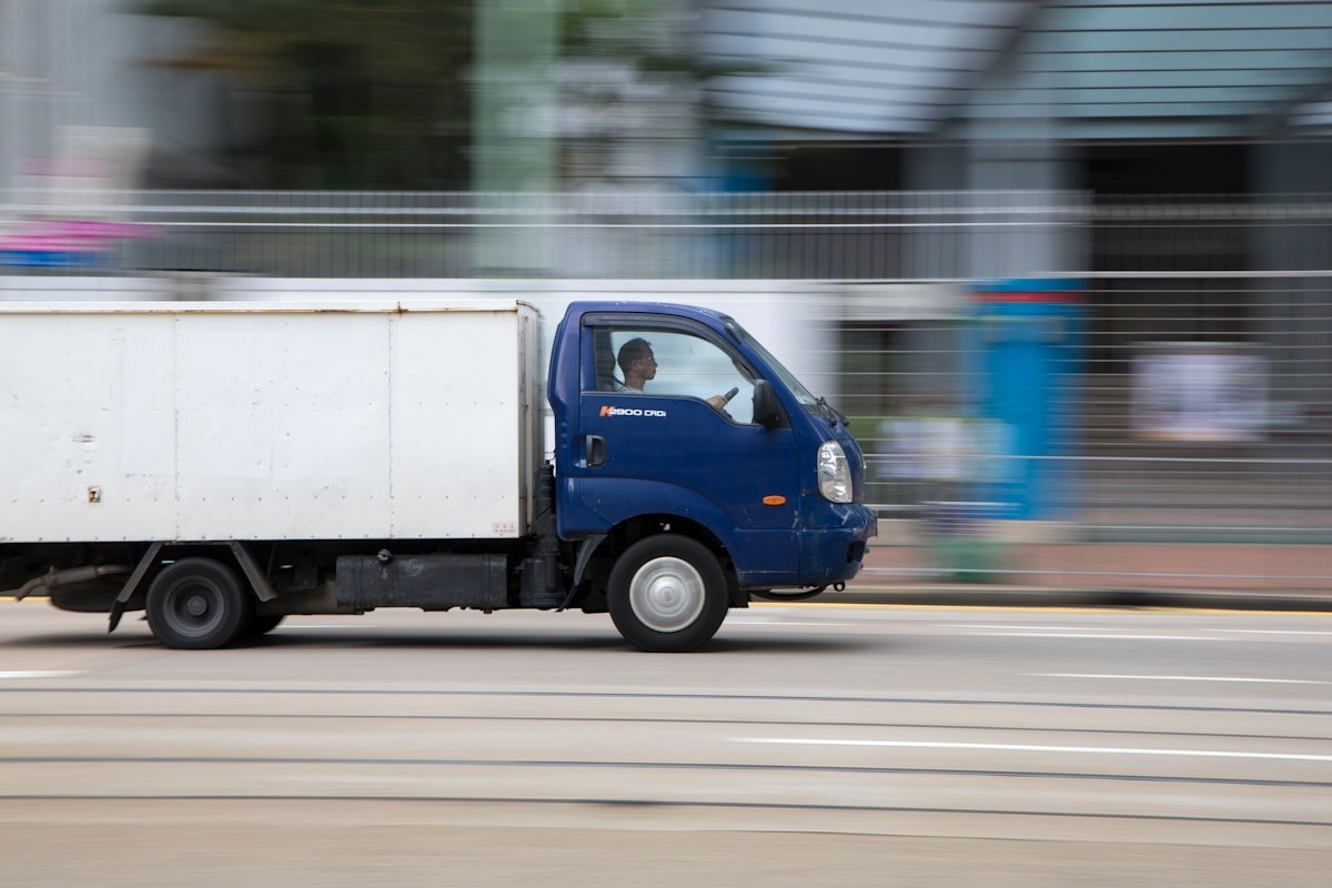 Camion de livraison bleu en mouvement rapide sur la route.