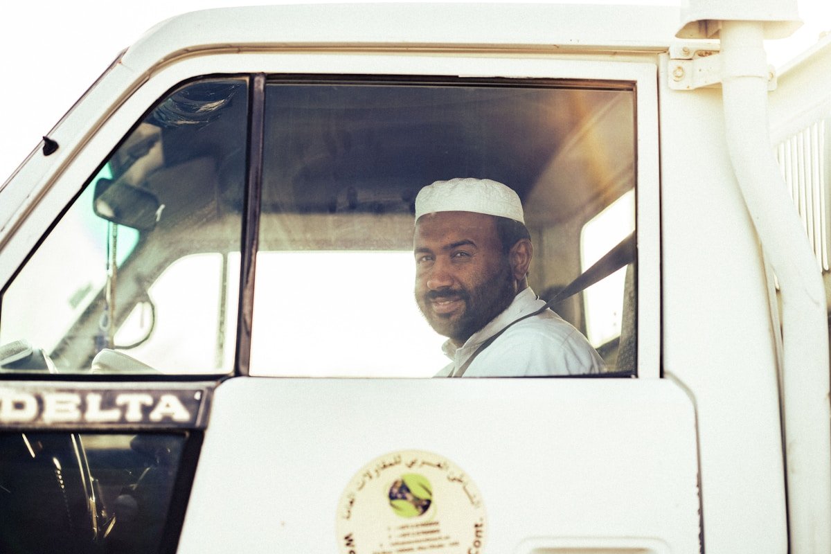 Homme africain souriant dans la cabine d'un camion Delta.