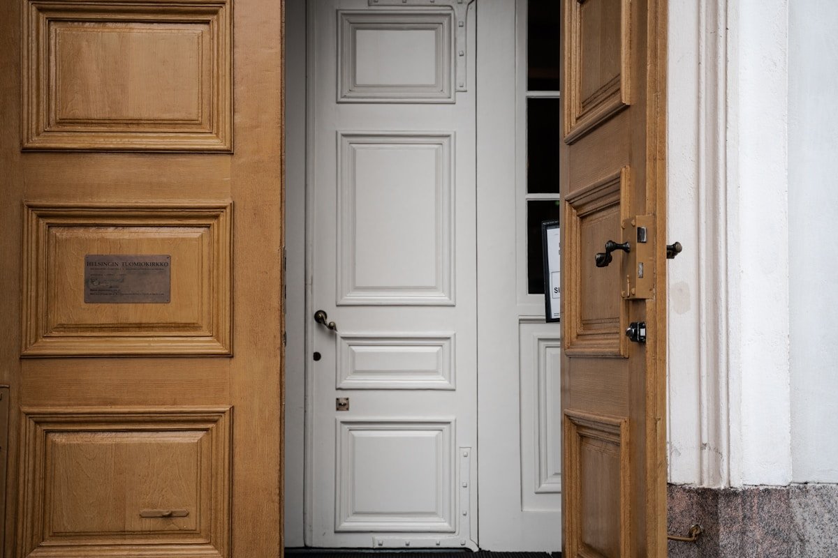 Porte d'entrée blanche avec encadrement en bois ancien.