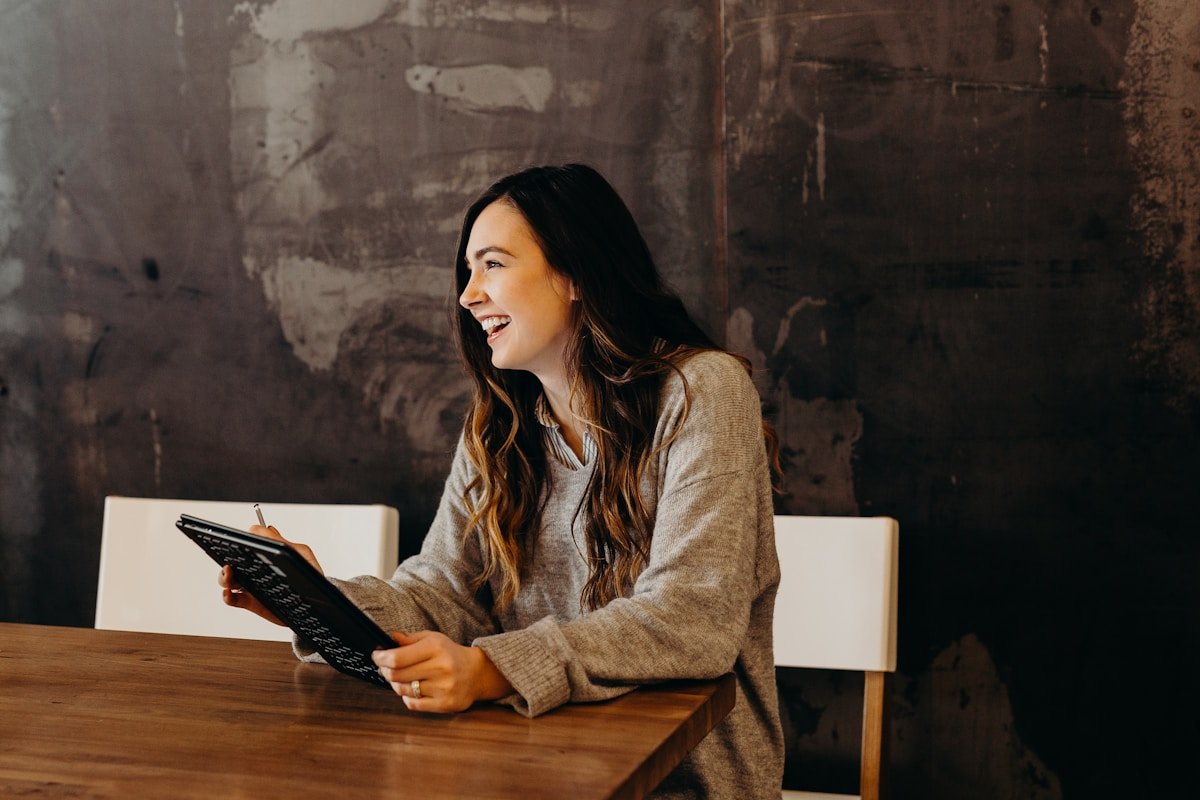 Femme souriante utilisant un clavier d'ordinateur dans un environnement sombre.