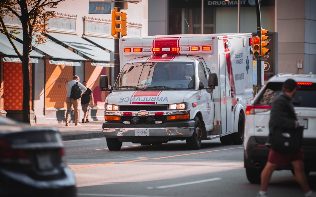 Ambulance d'urgence avec sirène et feux rouges dans une rue animée.