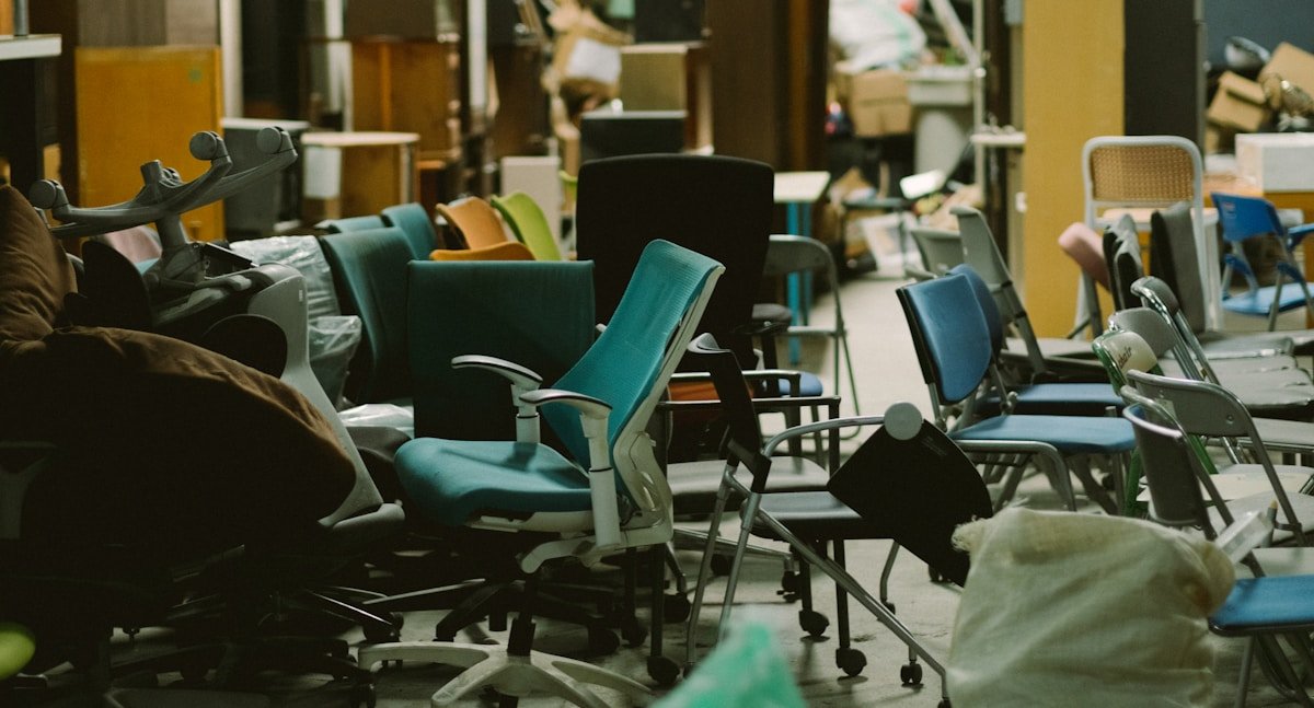 Chaises de bureau colorées et désordonnées dans un espace de travail encombré.