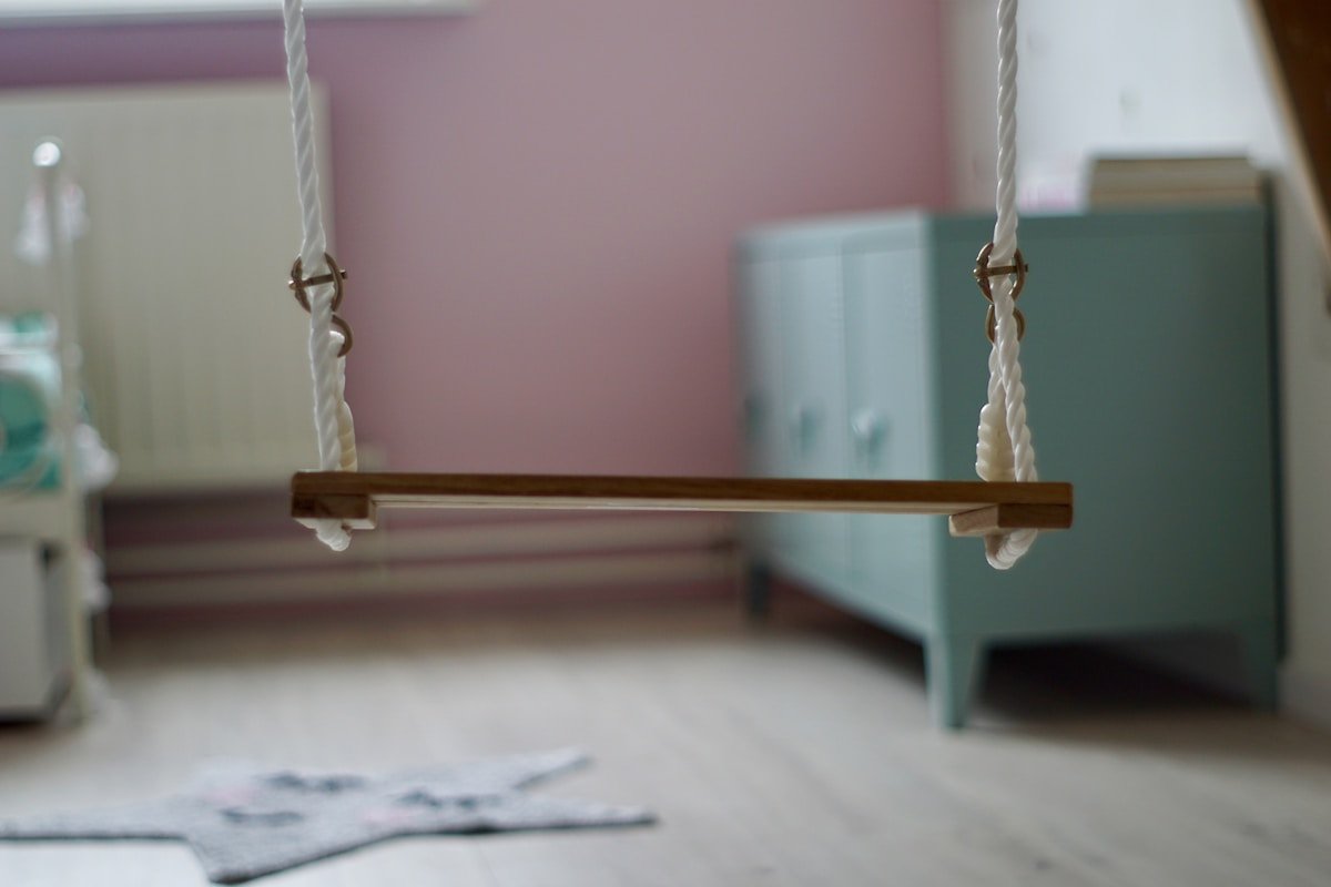 Balançoire suspendue dans une pièce rose et blanche.