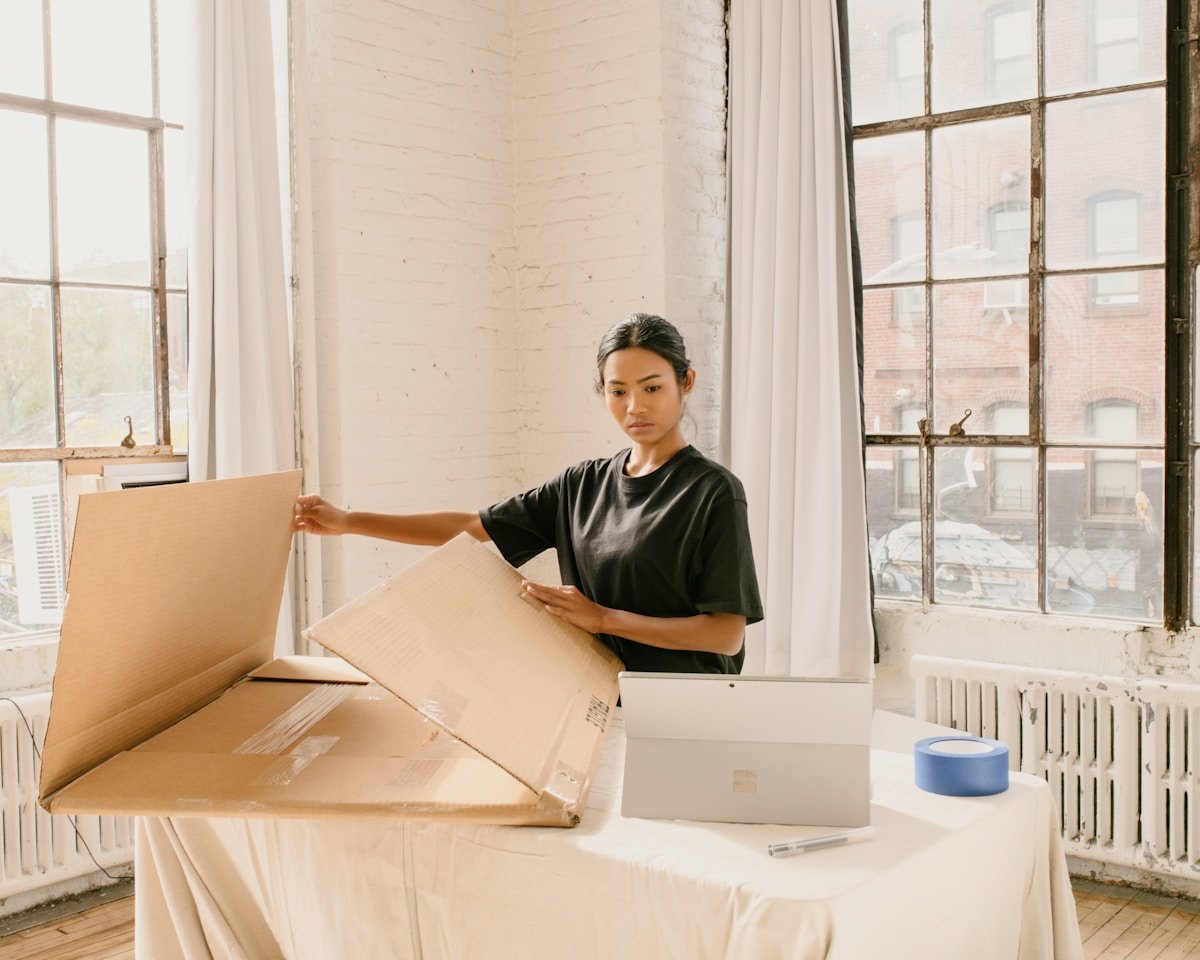 Femme asiatique emballant des boîtes dans un appartement lumineux.