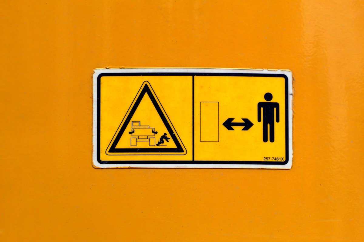 Panneau de signalisation jaune avec symboles de danger et de direction.