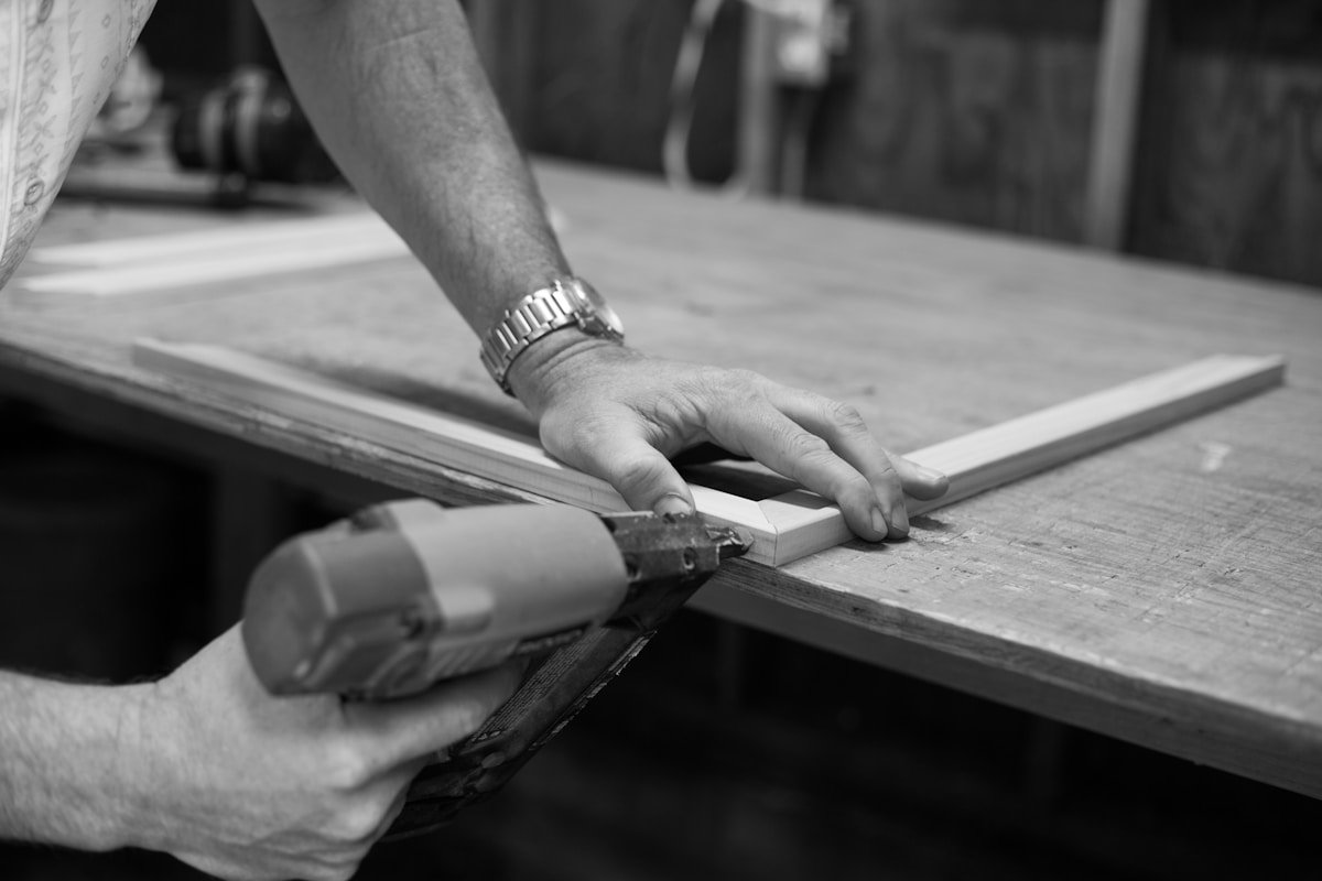 Mains d'un artisan travaillant le bois avec un outil.