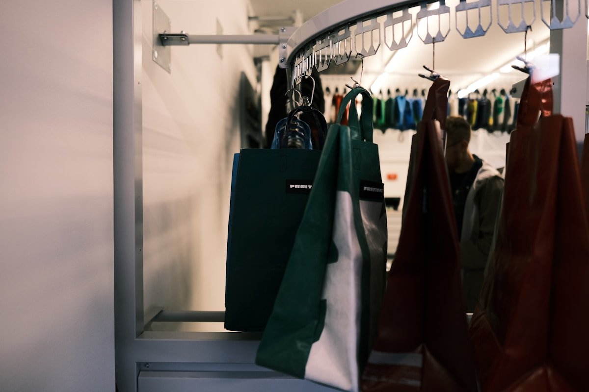 Penderie avec vêtements colorés et sacs de magasinage verts.