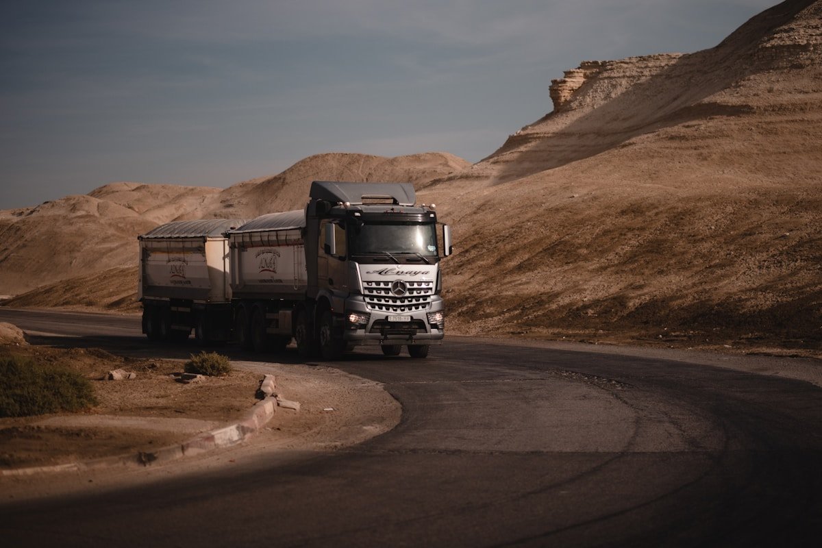 Camion de transport traversant un paysage désertique accidenté.