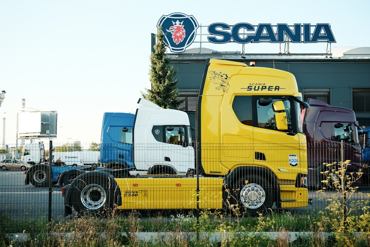Camions Scania jaune et bleu garés devant le bâtiment de la marque.