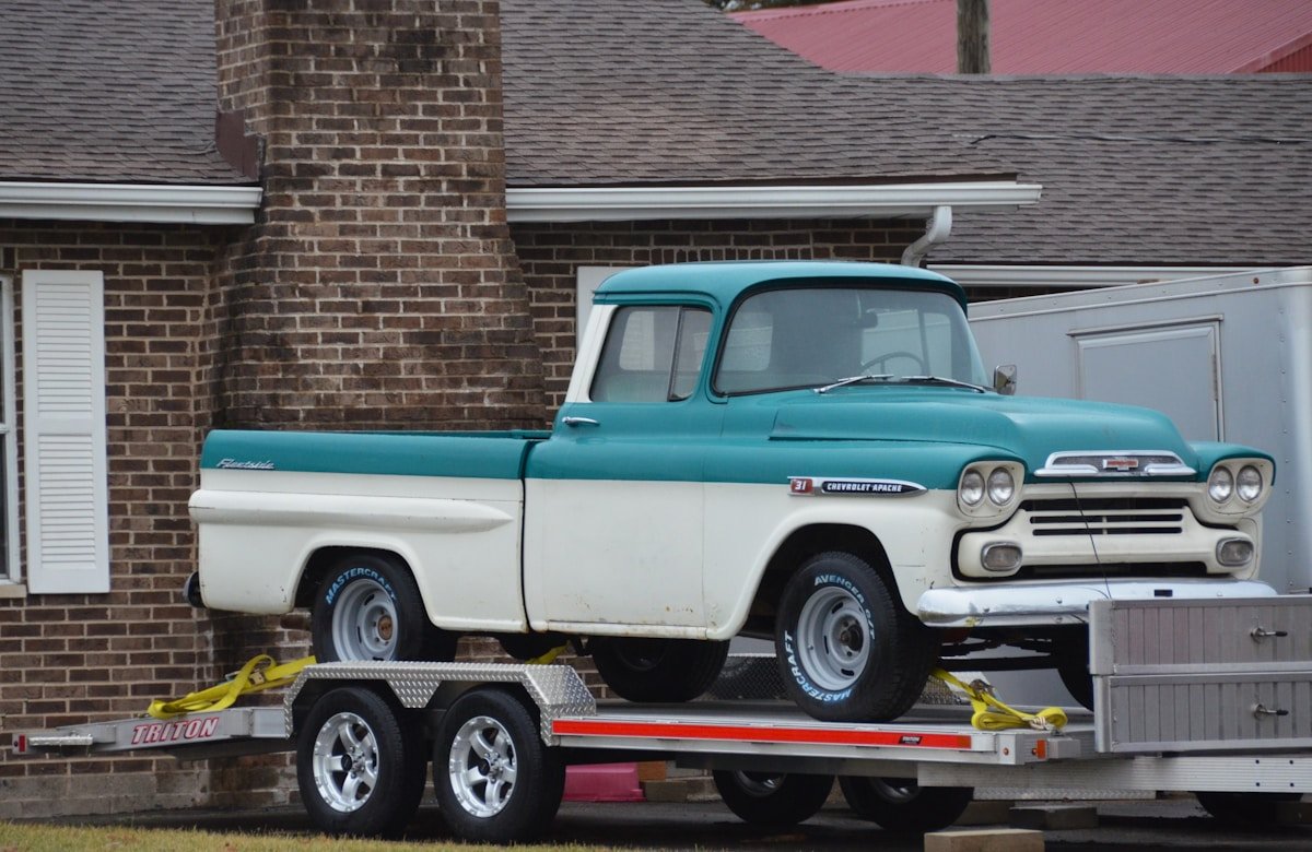 Camionnette vintage Chevrolet sur remorque, couleur turquoise et blanche.