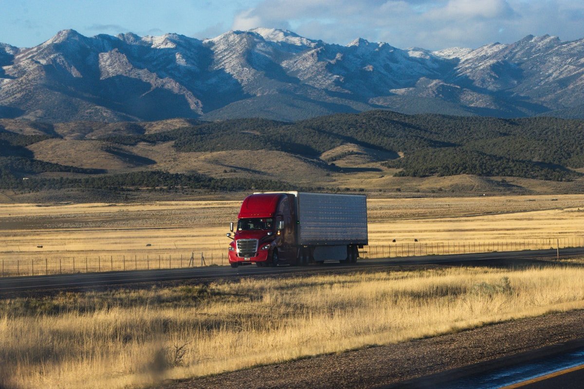 Camion rouge traversant un paysage montagneux enneigé.