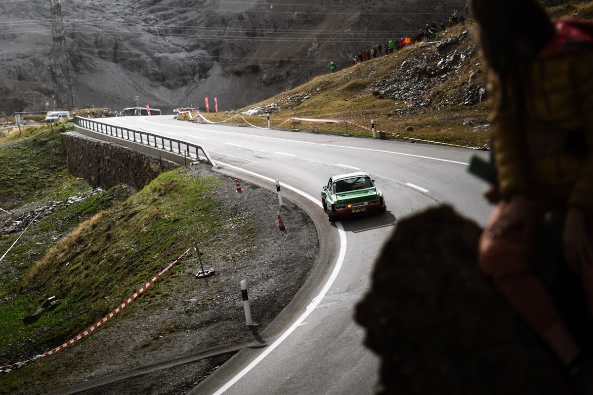 Route de montagne sinueuse avec voiture de course verte.