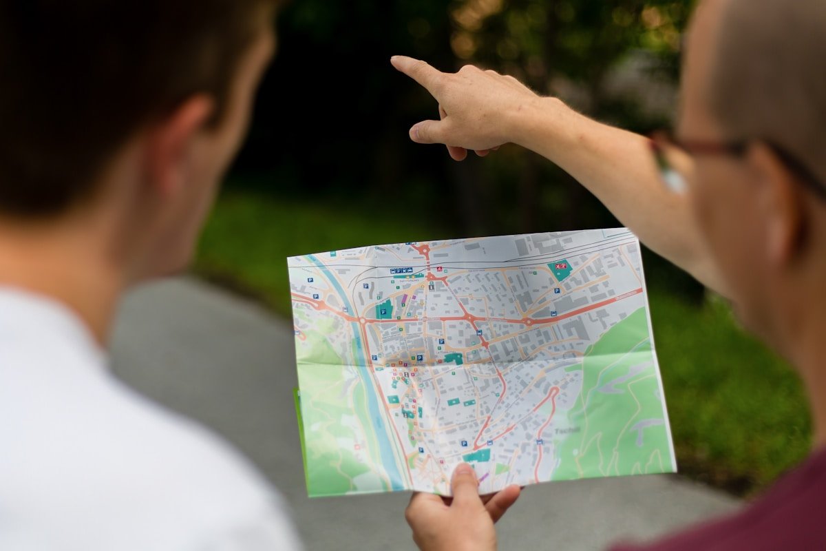 Personne tenant une carte géographique et pointant du doigt.