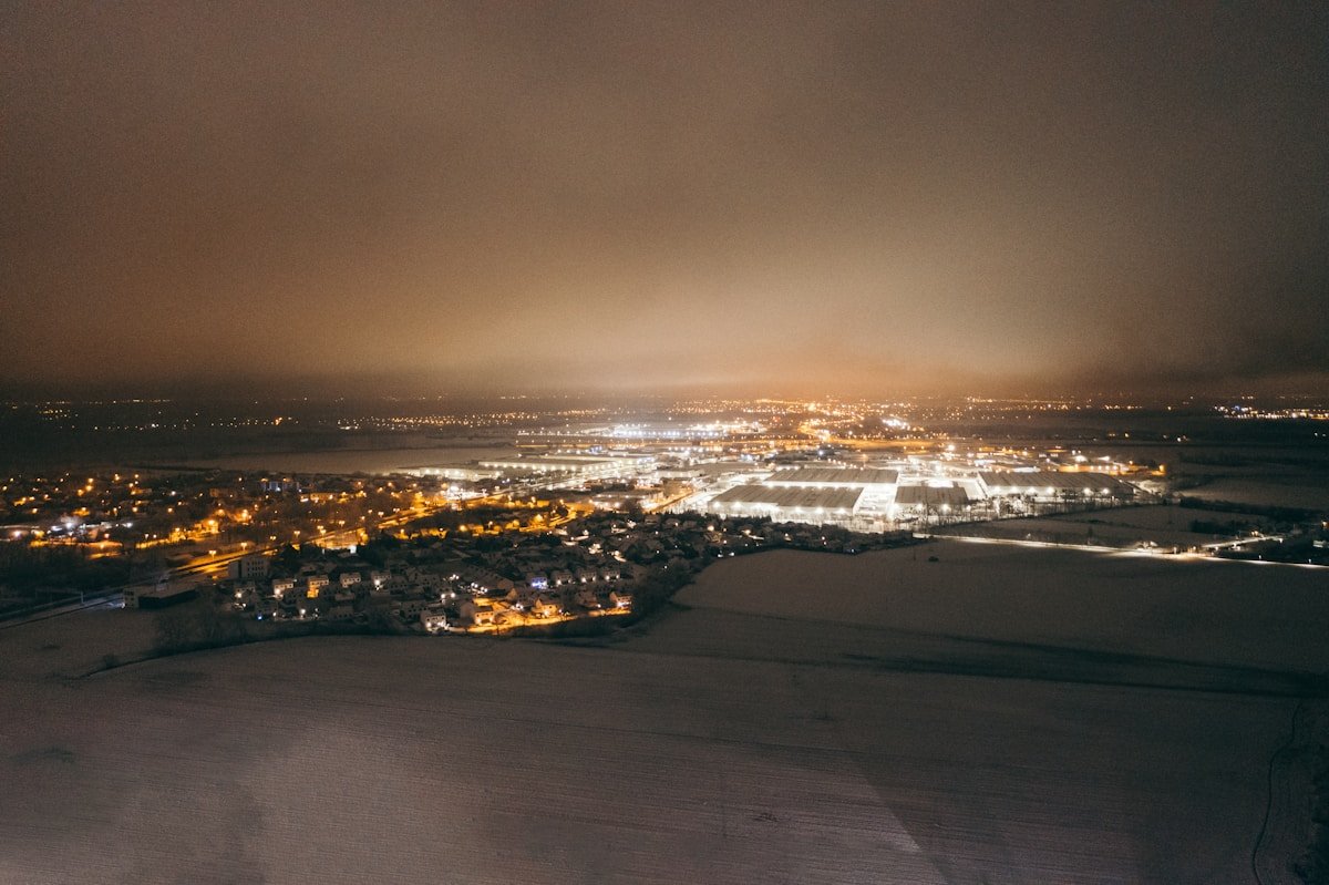Paysage urbain nocturne avec lumières scintillantes et horizon brumeux.