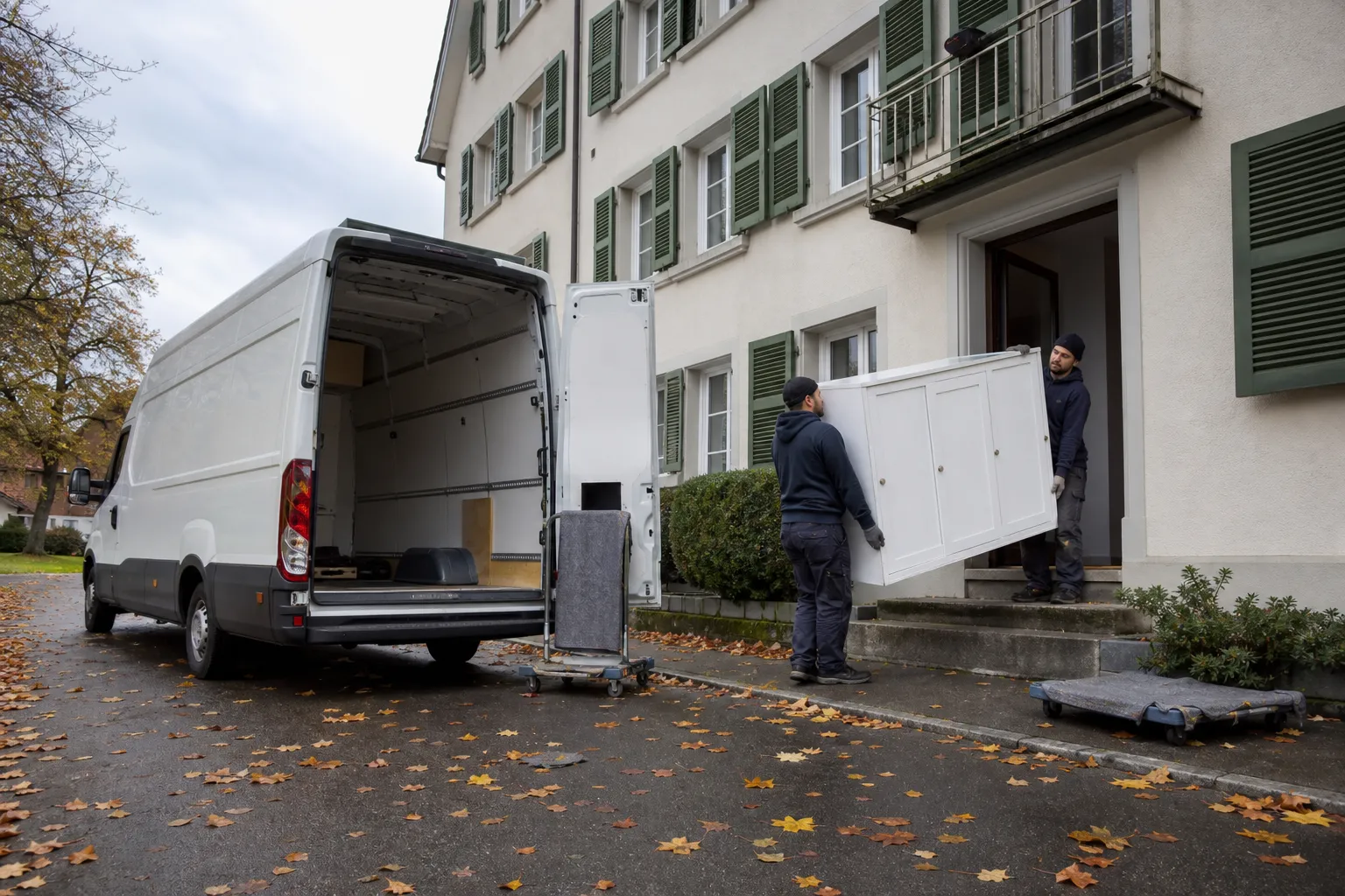 Déménagement d'un meuble dans un camion devant un bâtiment résidentiel en automne.