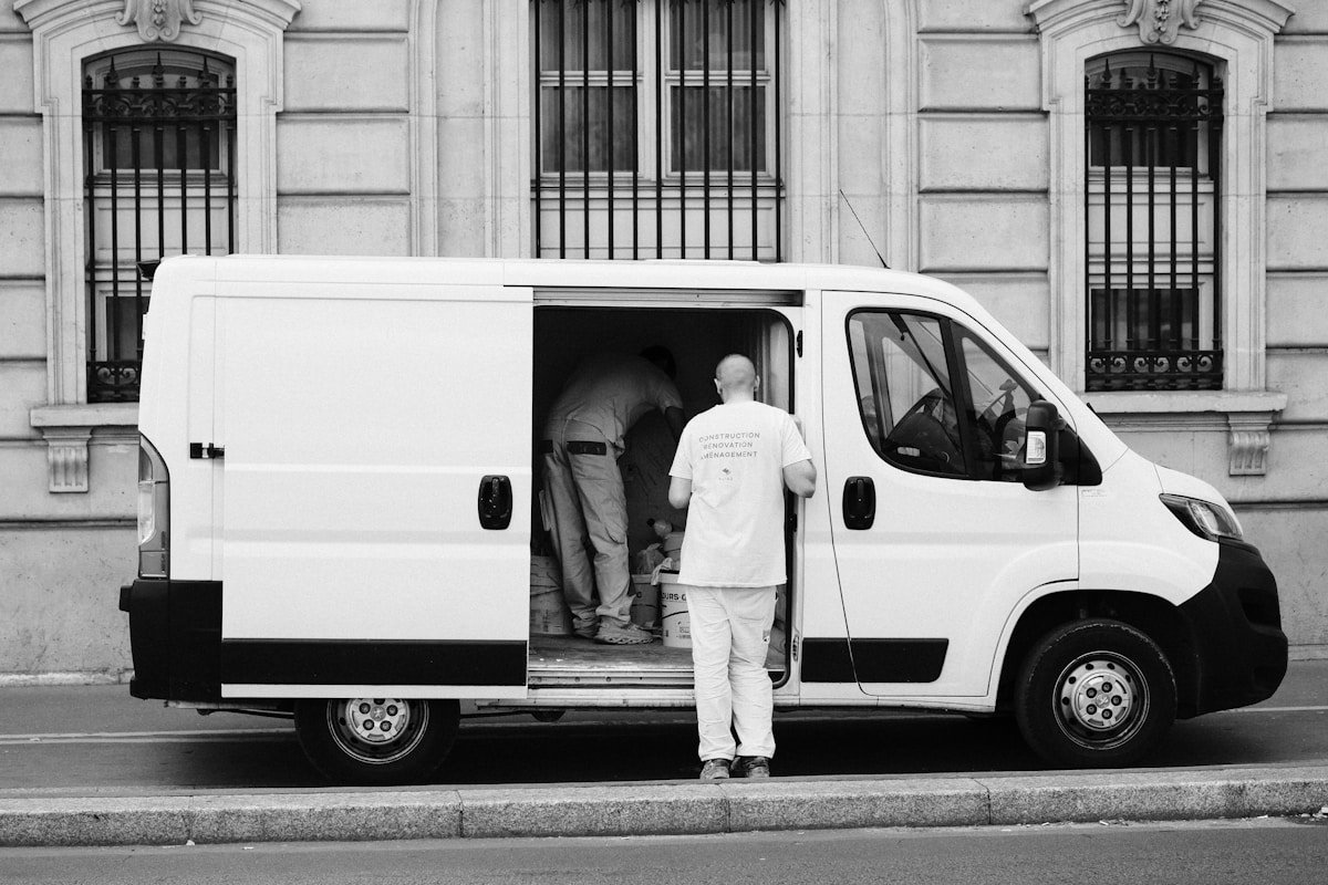 Camion de livraison blanc stationné devant un bâtiment historique.