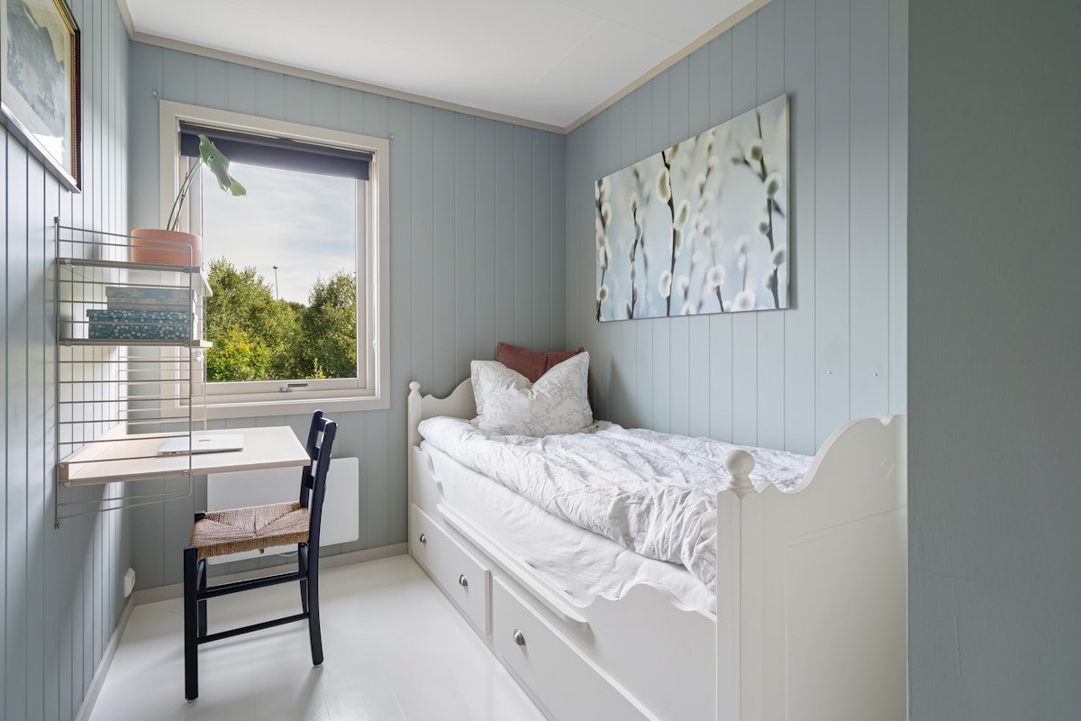 Chambre à coucher avec murs gris, lit blanc, bureau et chaise.