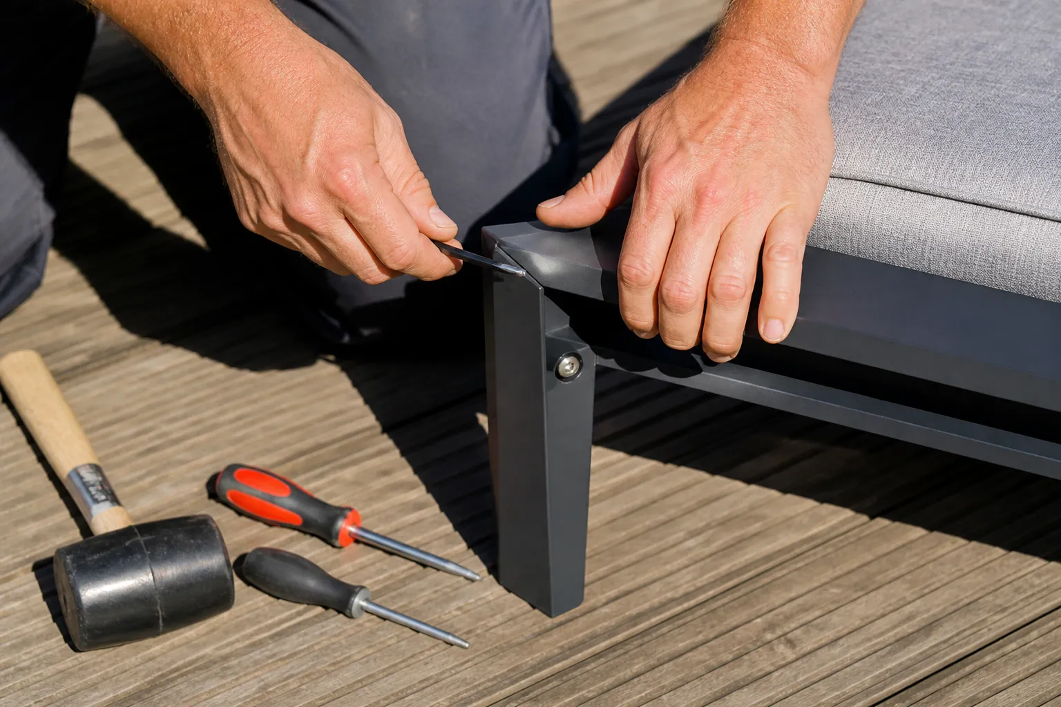 Mains d'un homme assemblant un meuble avec des outils.