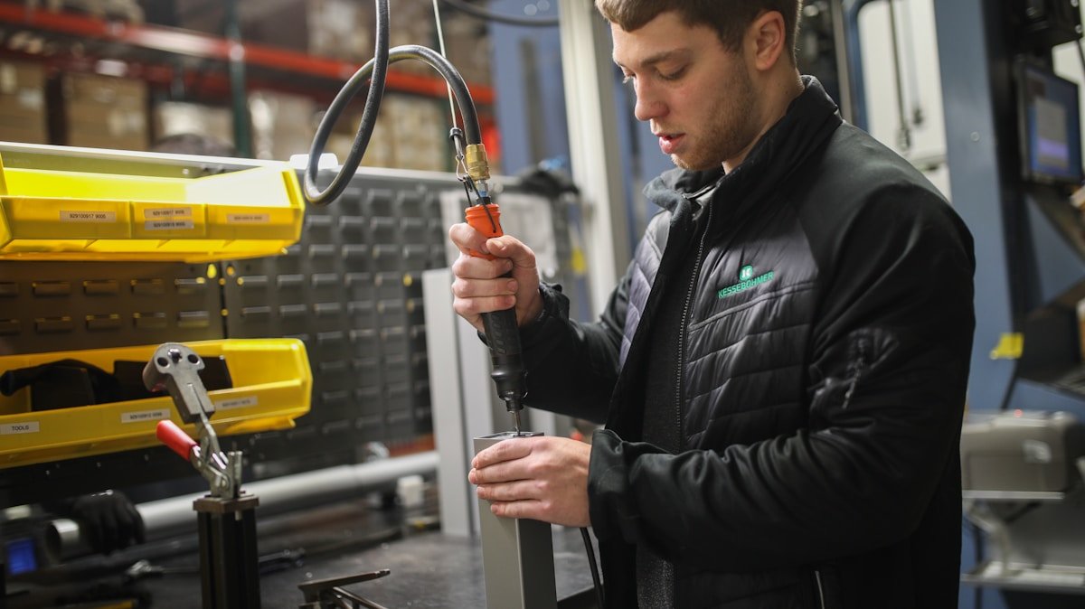 Homme en veste noire travaillant sur un équipement industriel dans un atelier.