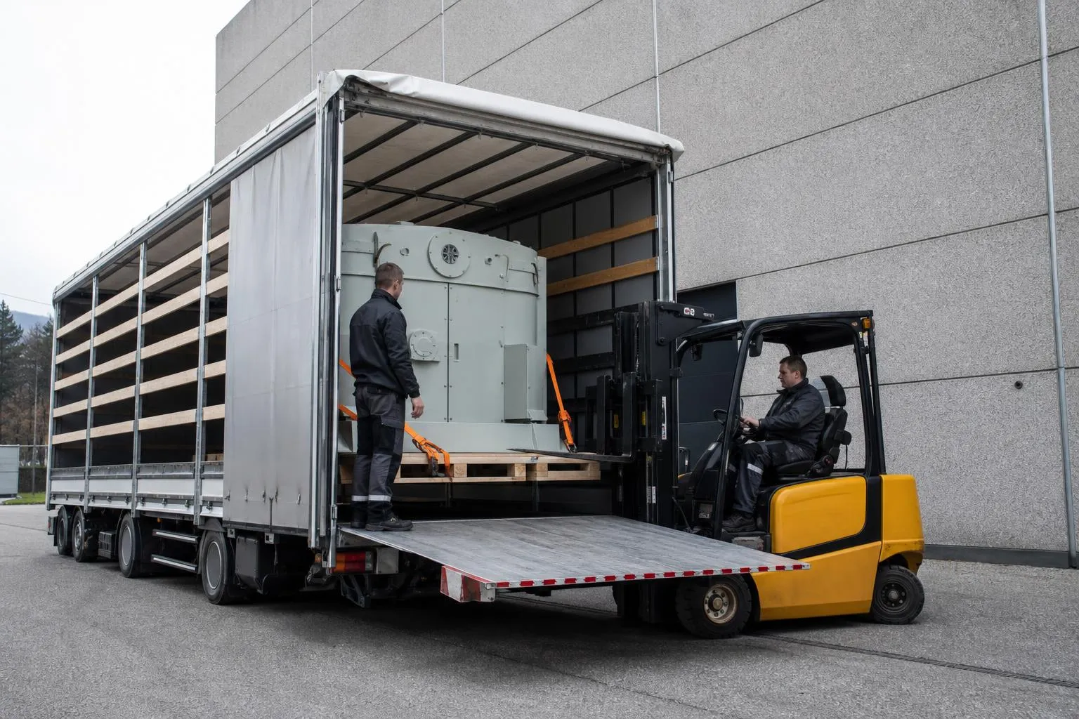 Chariot élévateur charge une machine dans un camion ouvert