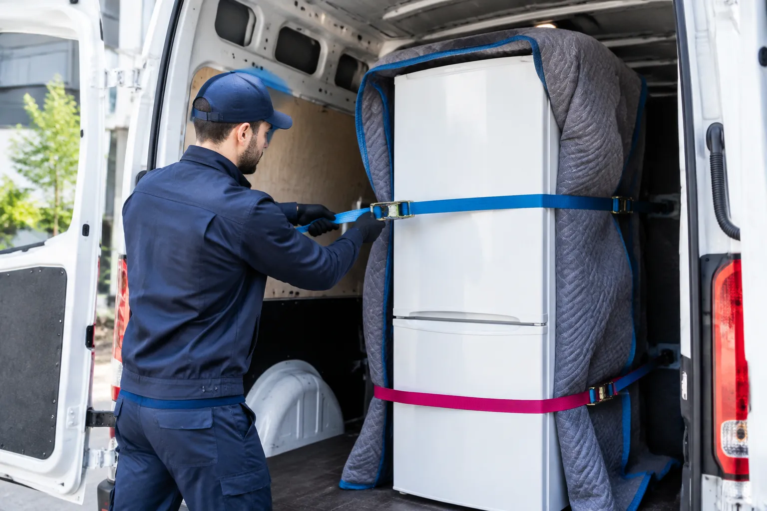 Déménageur attachant un réfrigérateur dans une camionnette.