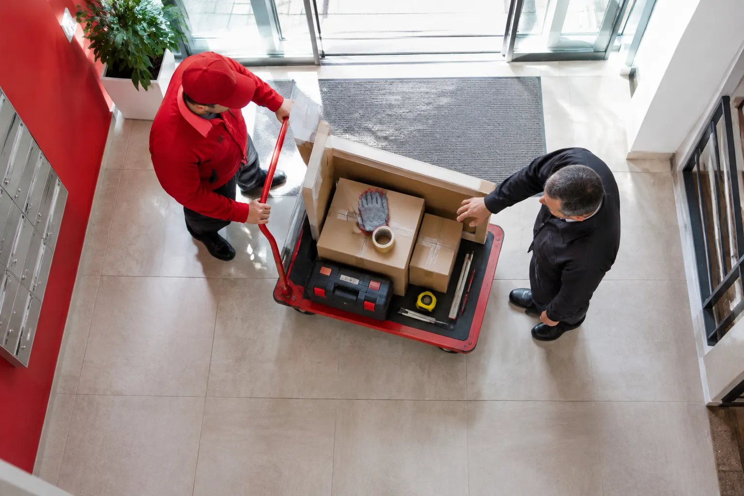 Deux déménageurs chargent des cartons sur un chariot.